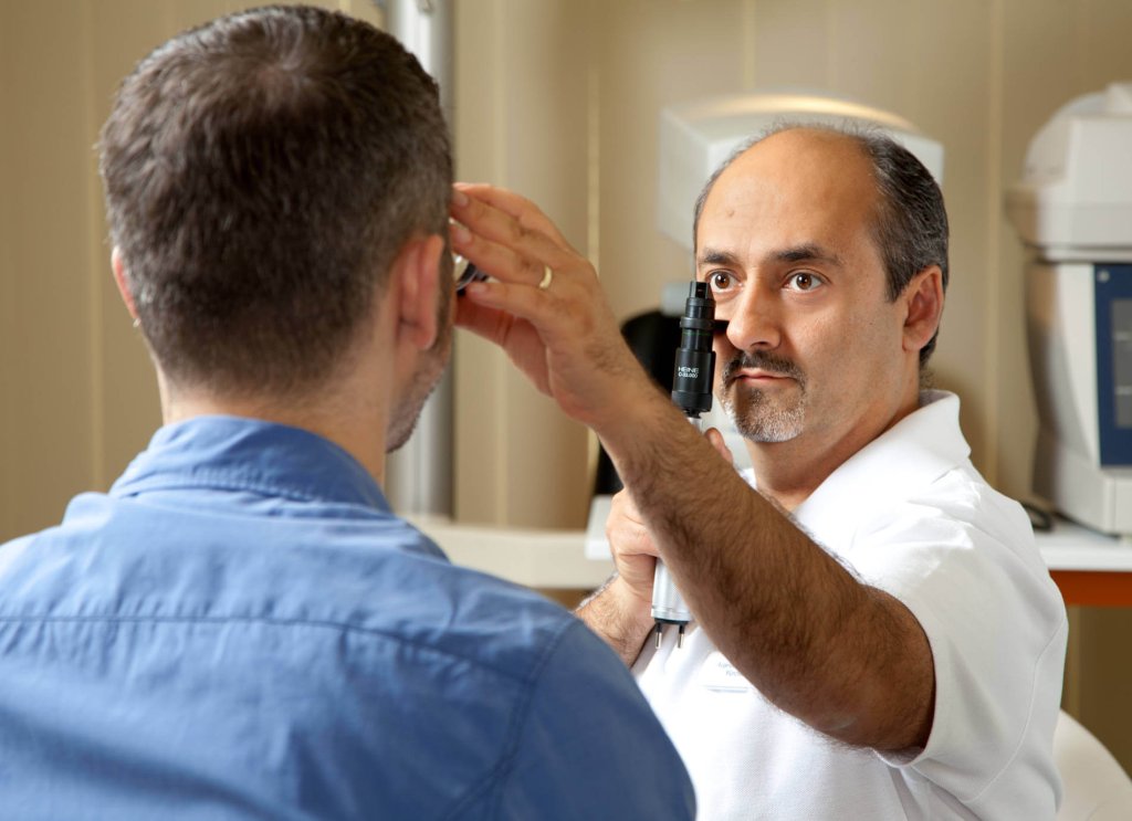 Prof. Parasta untersucht das Auge eines Patienten mit dem Ophthalmoskop.